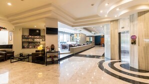 A modern hotel lobby with a marble floor, a reception desk, a bar area, and seating. - Hotel Misión Toreo Centro De Convenciones (Naucalpan)