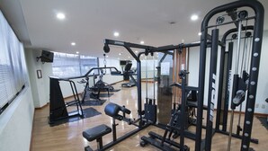 Een sportschool met diverse fitnessapparaten, waaronder een bankdrukapparaat, een squatsysteem en een kabelmachine.