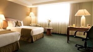 A hotel room with two beds, a desk, a chair, and a small table with a vase of flowers. - Hotel Misión Toreo Centro De Convenciones (Naucalpan)