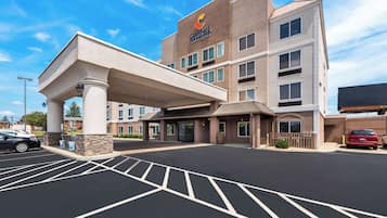 Welcome to Comfort Inn & Suites, featuring a modern entrance with a covered walkway and designated parking spaces.
