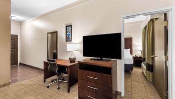 Habitación de hotel con escritorio, silla, televisor y cama.