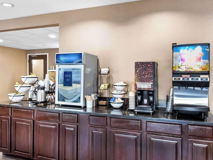 Een hotel receptie met een zelfbedieningsdrankstation, een koffieapparaat en een magnetron.
