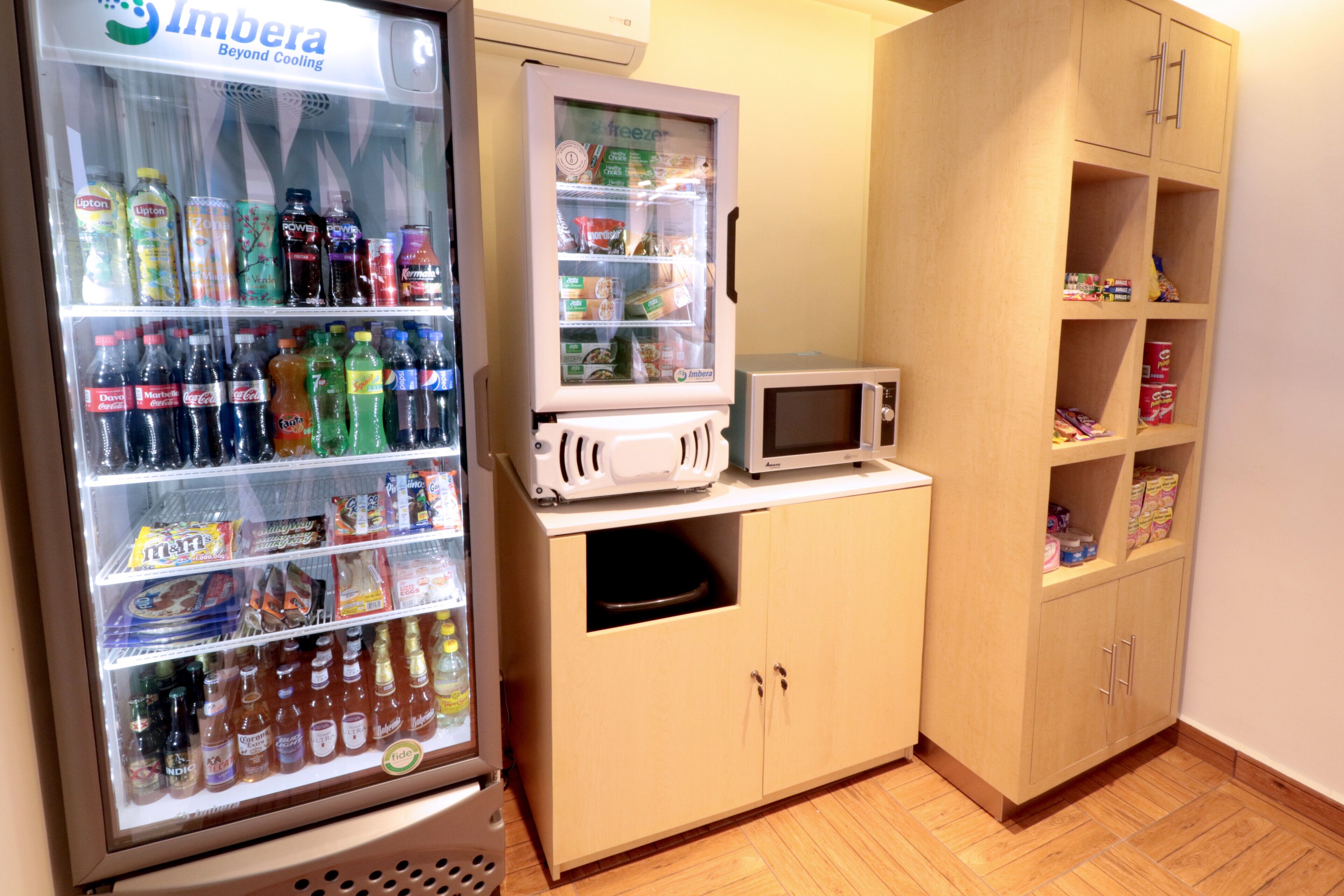 A kitchenette with a refrigerator, microwave, and wooden cabinets.