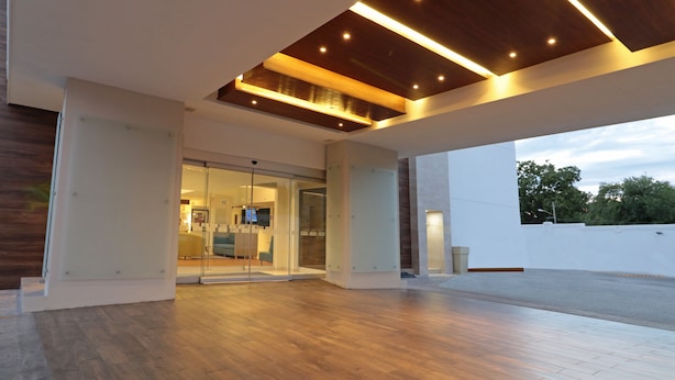 Une entrée moderne avec des portes en verre, un plancher en bois et un plafond doté d’un éclairage encastré.