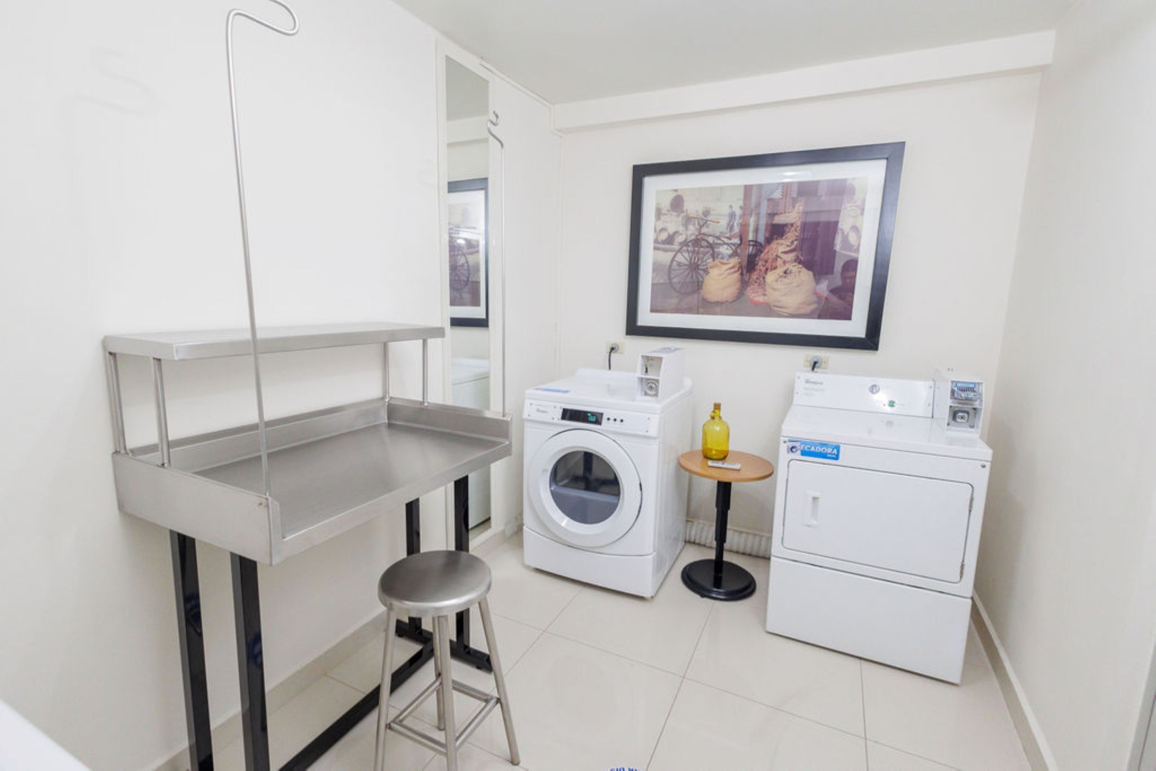 A compact laundry room with a washing machine, dryer, and a small stool.