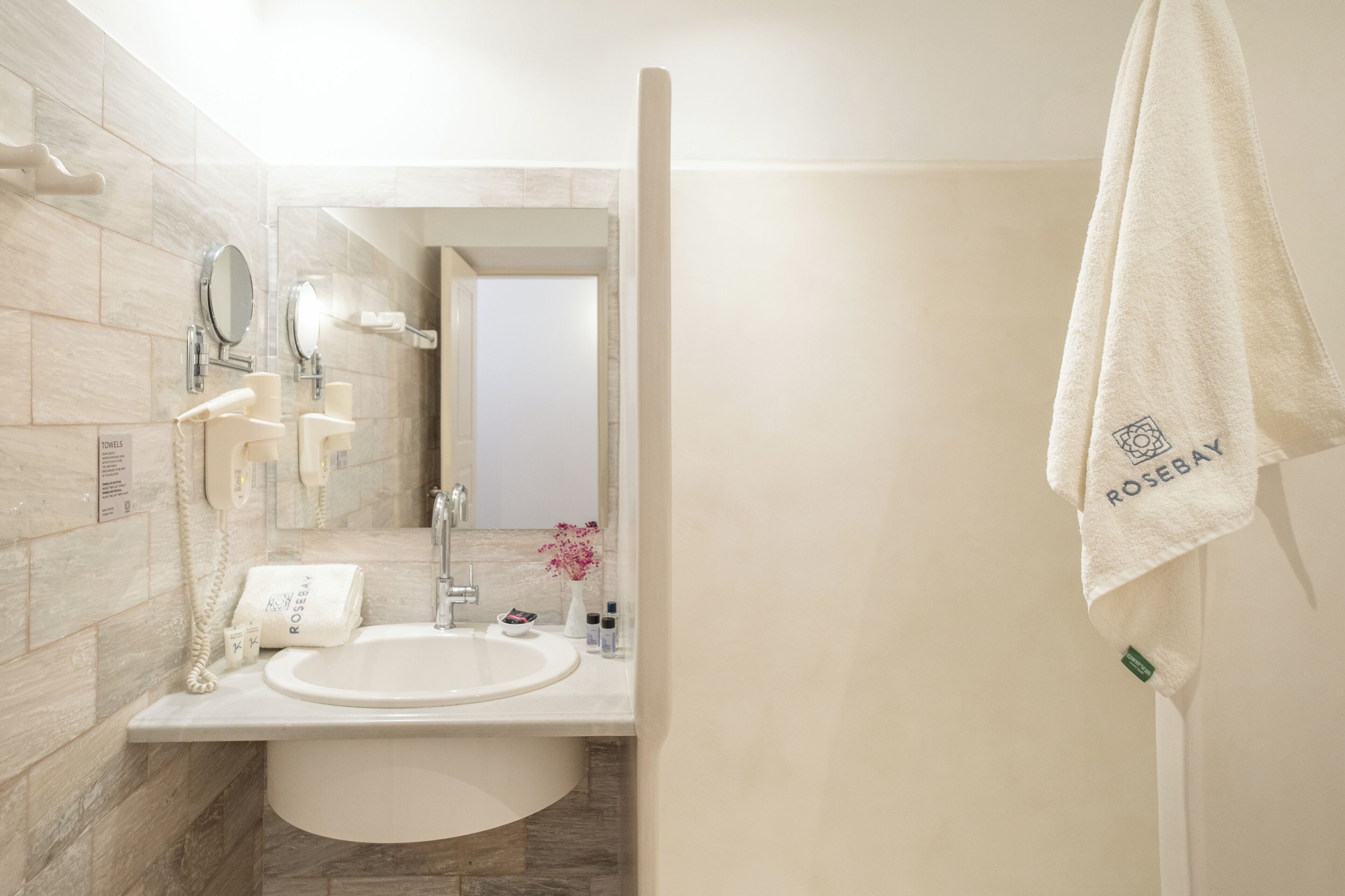 A bathroom with a sink, mirror, towel rack, and a visible door leading to another room.