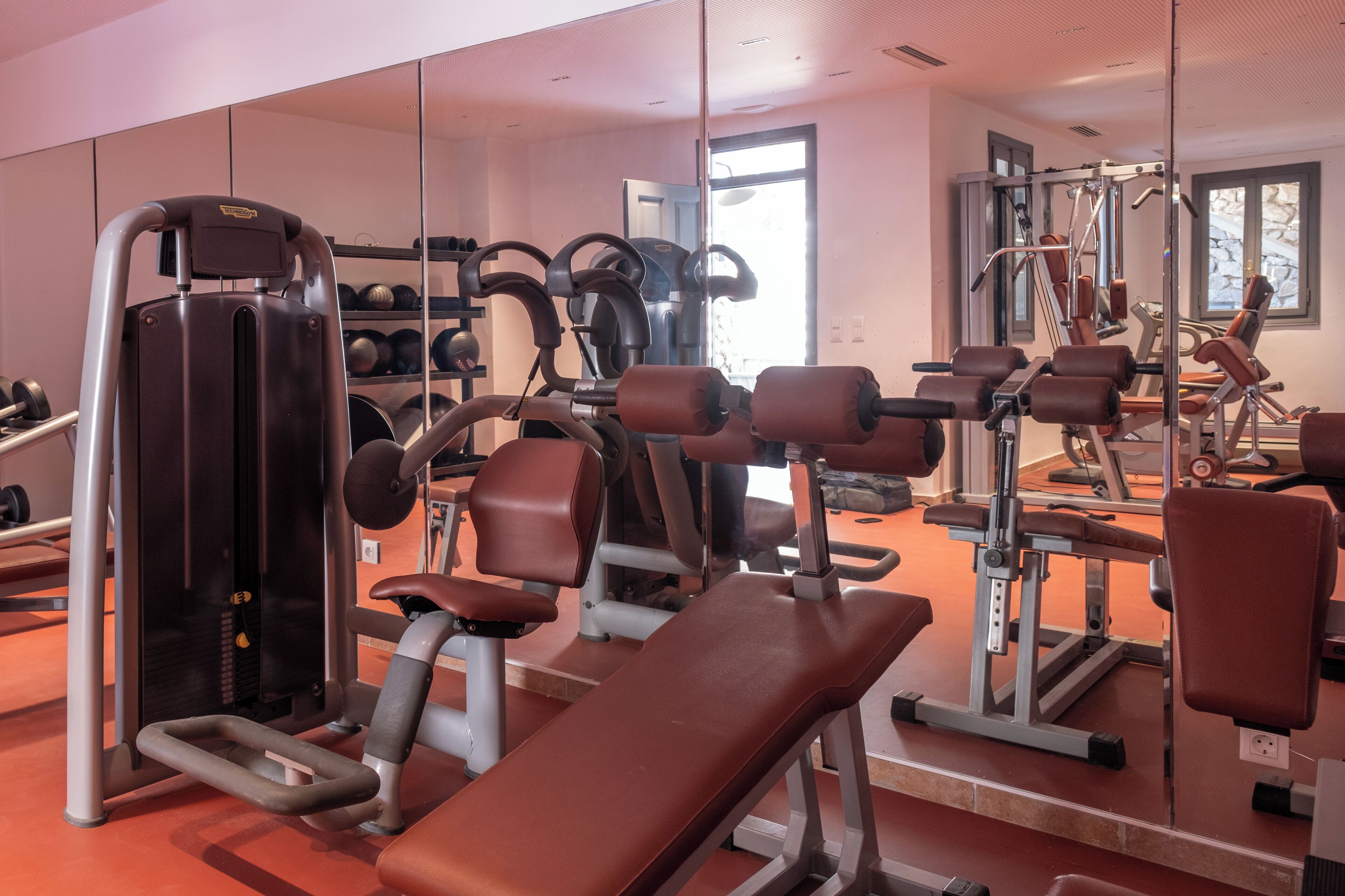 A gym with exercise equipment, a mirrored wall, and a window with a view.