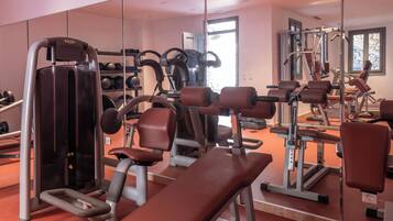 A gym with exercise equipment, a mirrored wall, and a window with a view.