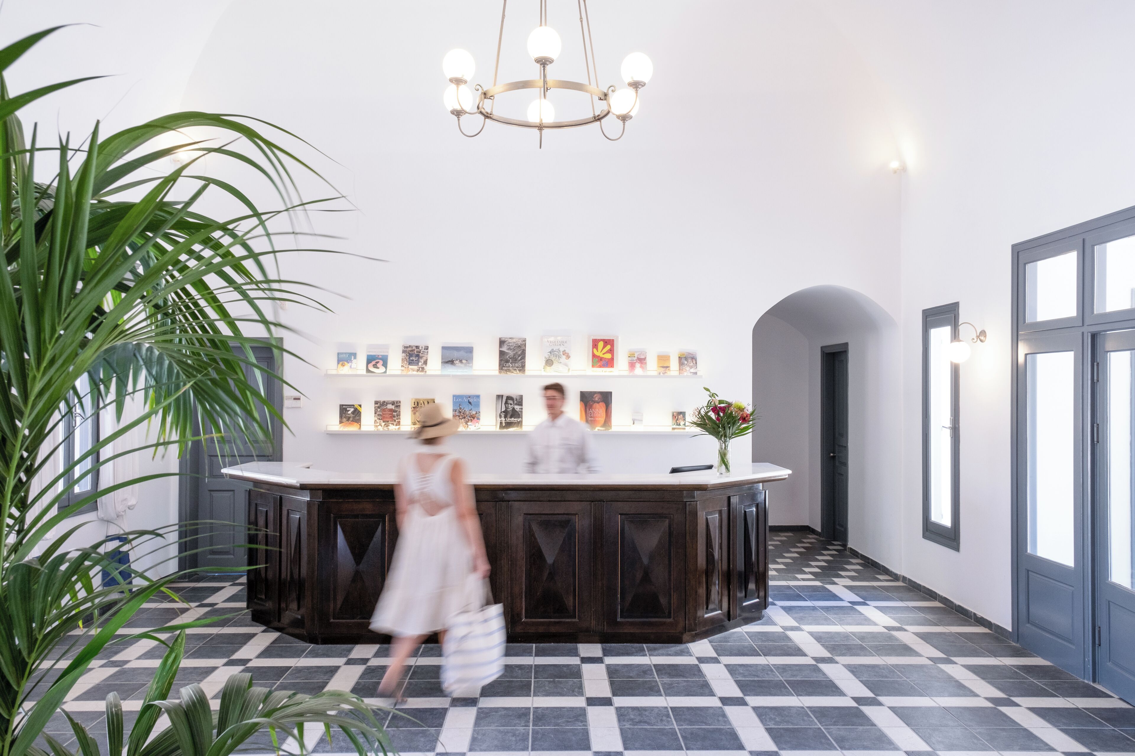 A reception desk with a checkered floor, a chandelier, and a wall with framed pictures.
