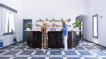 A reception area with a check-in counter, potted plants, and a tiled floor.
