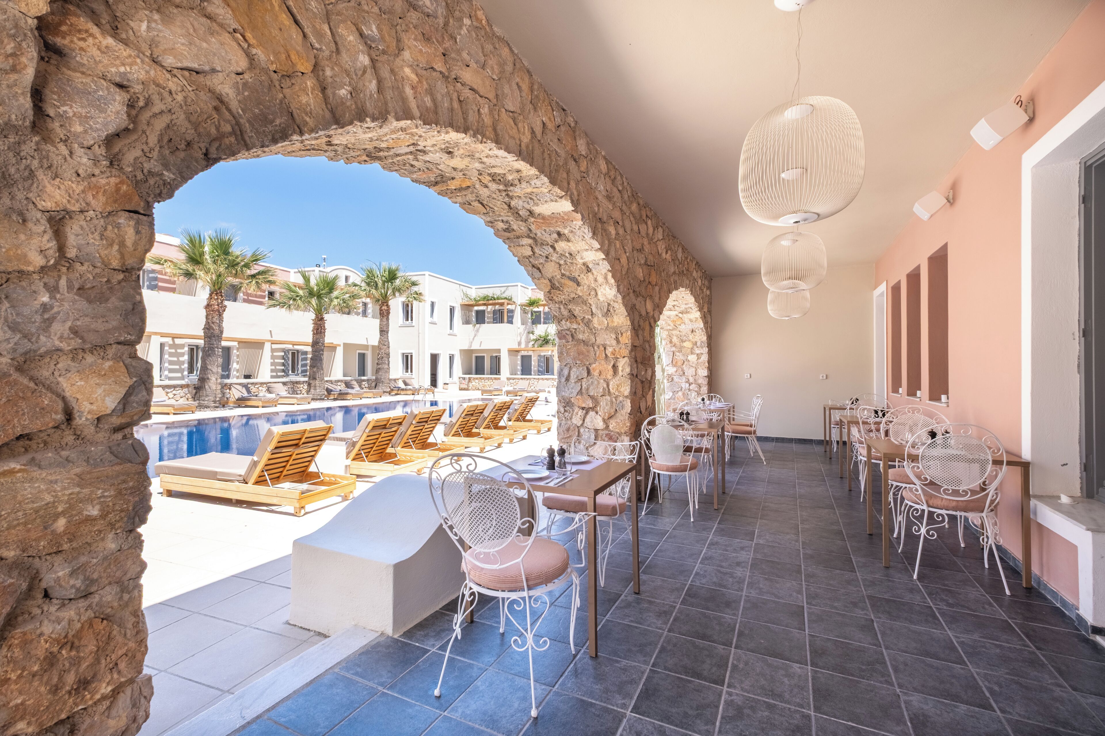A rooftop terrace with a pool, lounge chairs, and dining tables.