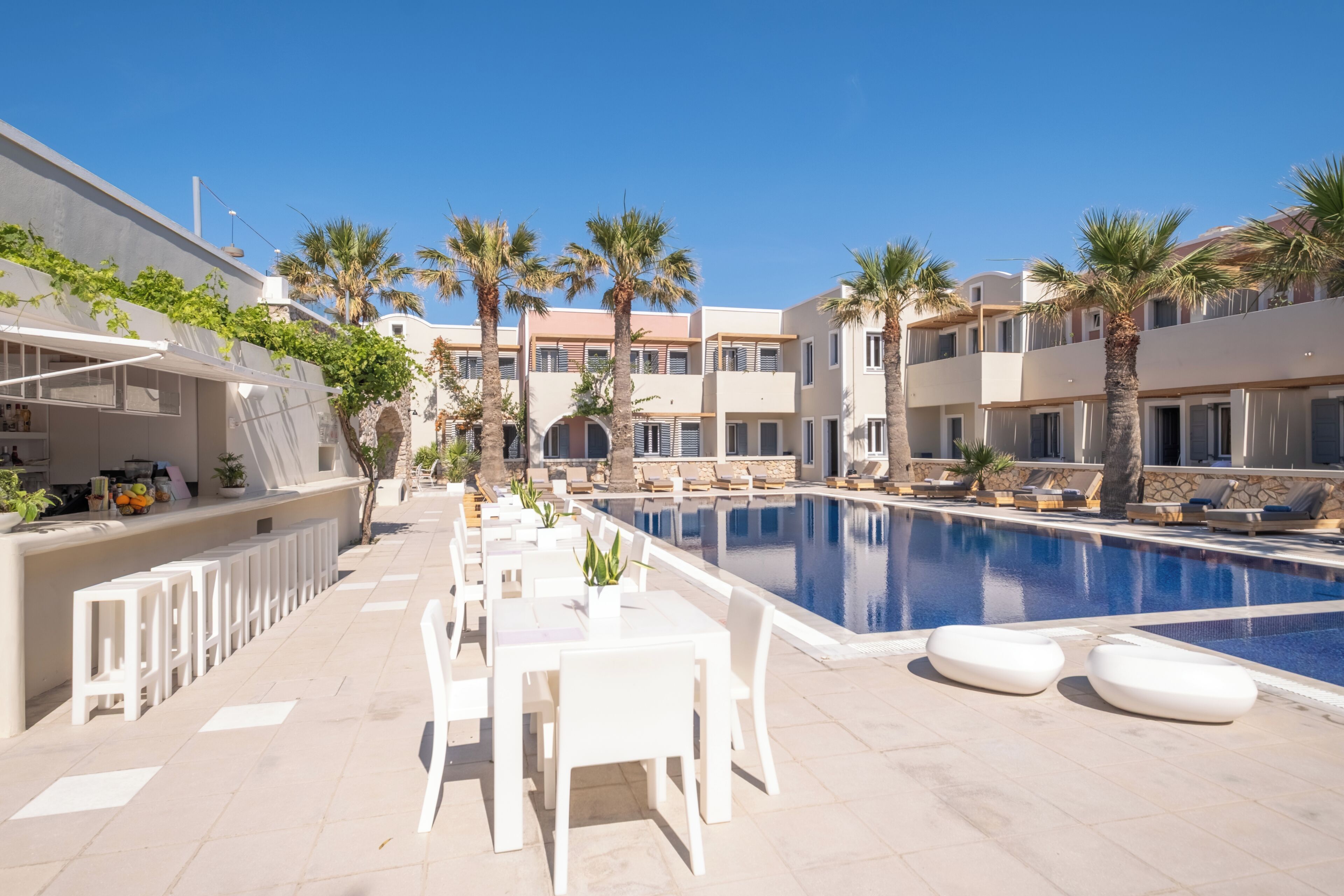 A poolside area with lounge chairs, a pool, and a bar area with seating.