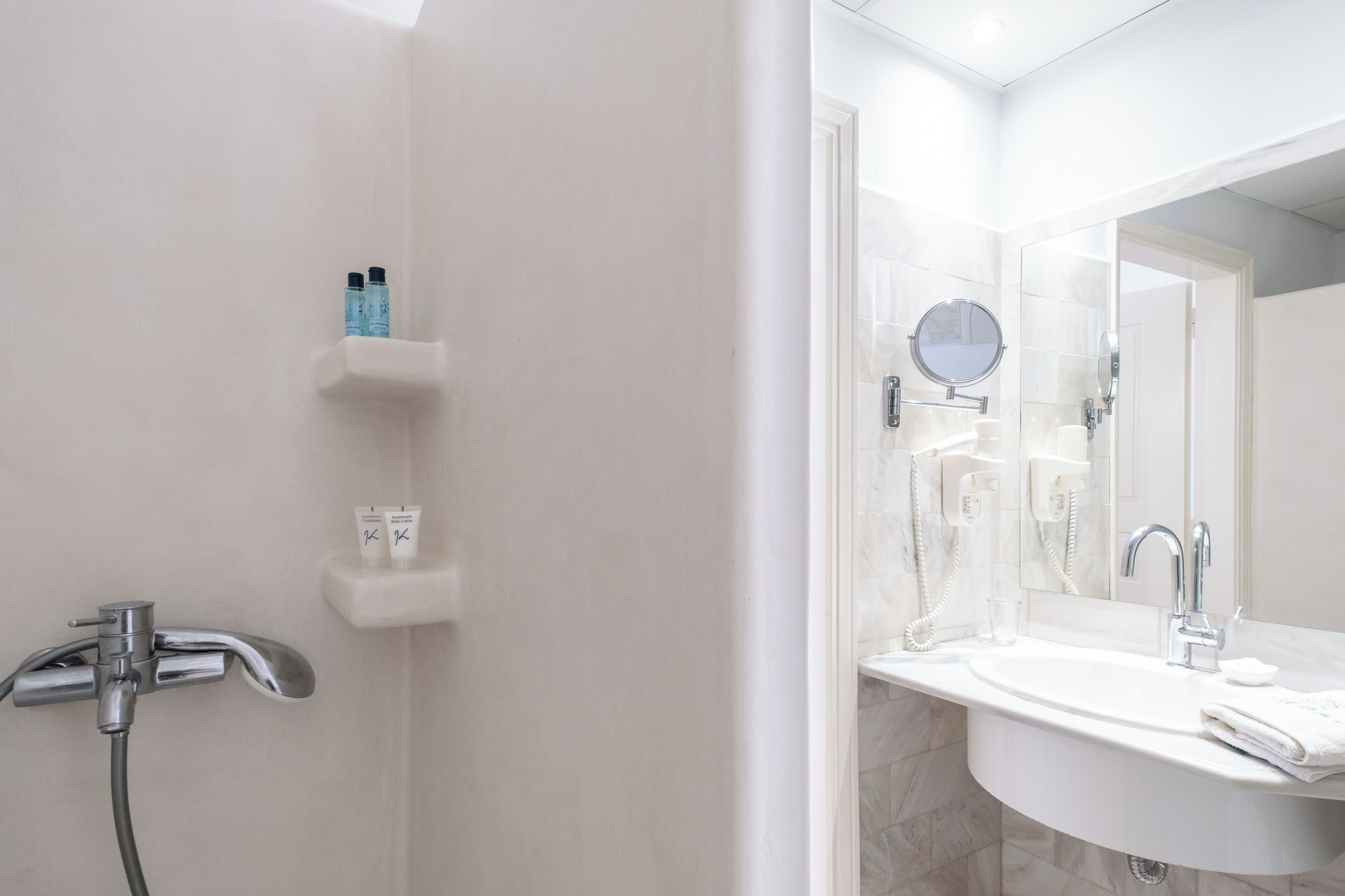 Une salle de bain avec une douche, un lavabo avec un miroir et des articles de toilette rangés sur une étagère.