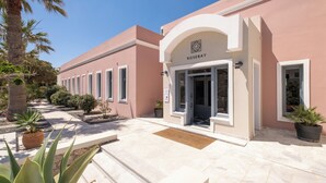 A building with a pink facade, a sign reading 'ROSEBAY,' and a clear sky. - Rosebay Hotel (Santorini)