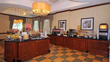 Un espace pour le petit-déjeuner dans un hôtel, avec un sol à carreaux, un comptoir en bois et divers plats proposés pour le petit-déjeuner.