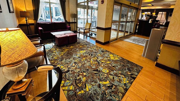 A hotel lobby with a red sofa, a patterned rug, and a reception desk. - Hampton Inn Alexandria-Old Town/King St. Metro (Alexandria)