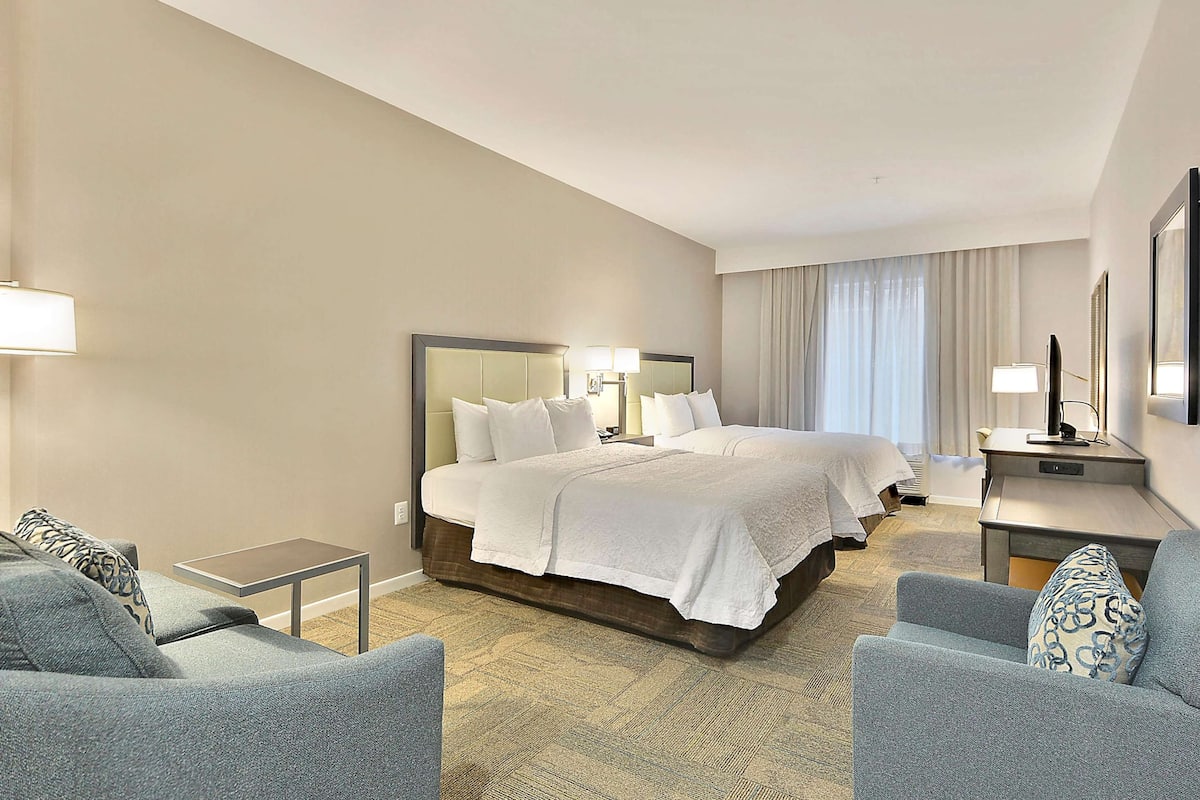A hotel room with a large bed, two bedside tables, a desk, and a chair.