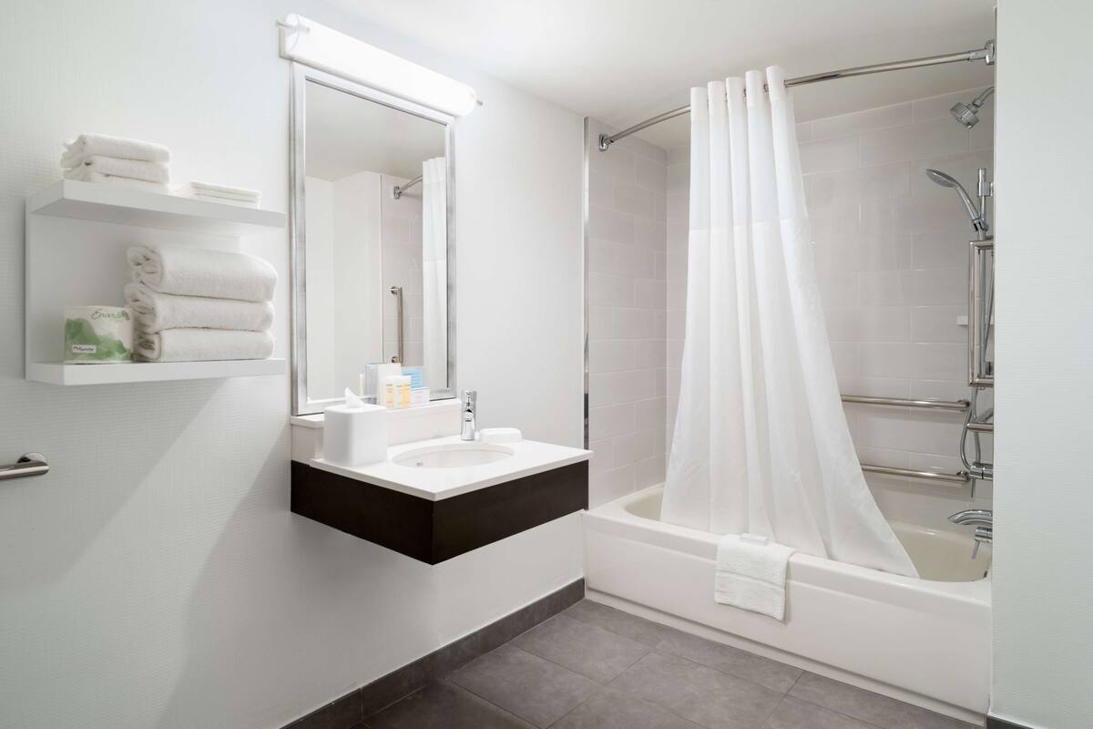 A modern bathroom with a white sink, mirror, and shower area.