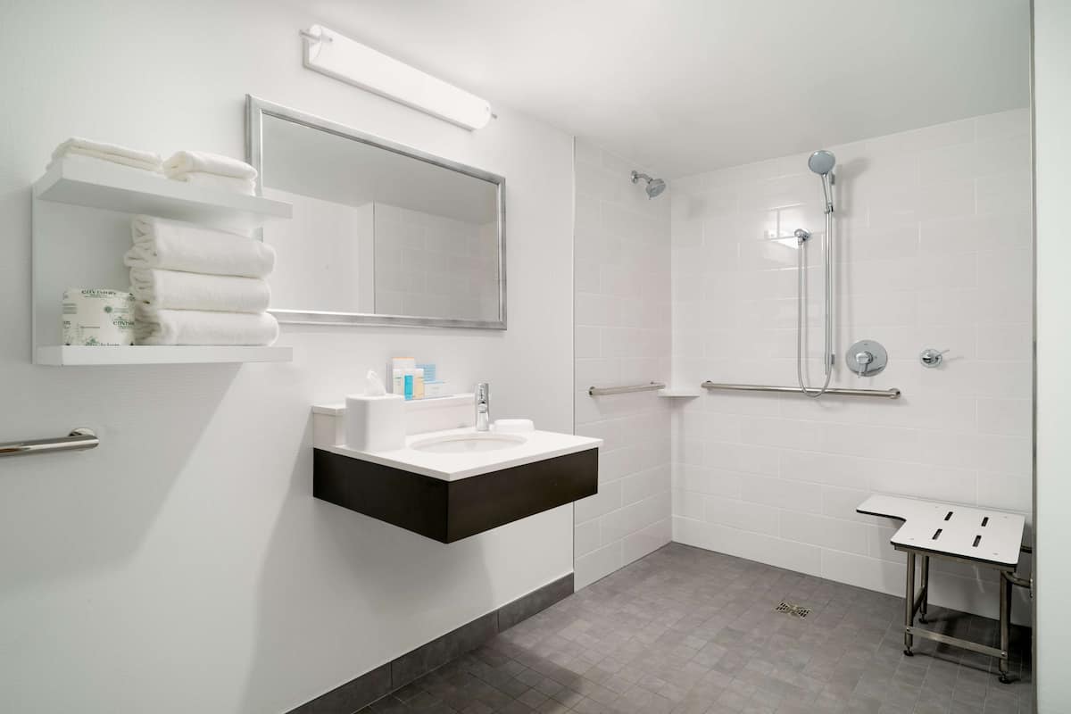 A modern bathroom with a white sink, mirror, and shower.