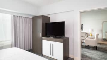 Habitación de hotel con cama, televisor en un mueble, sofá y lámpara.