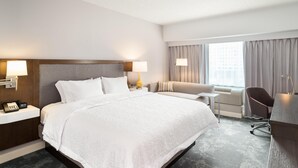 Una habitación de hotel con una cama grande, mesitas de noche con lámparas, un escritorio y una silla.