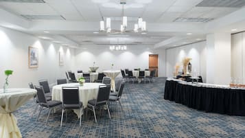 A conference room with round tables, chairs, and a black draped table.