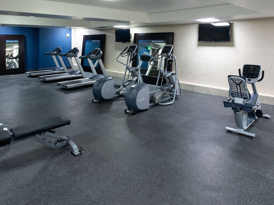 A gym with treadmills, elliptical machines, and a bench.