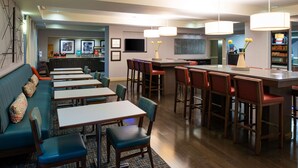 Un restaurant moderne doté d’un bar, de banquettes et de chaises hautes.