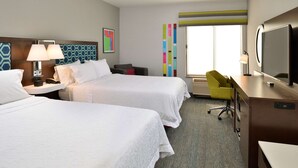 Une chambre d’hôtel avec deux lits, un bureau, une chaise, une télévision et une fenêtre avec des rideaux.