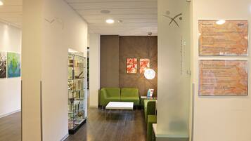 Un interior moderno con un sofá verde, una mesa blanca y vitrinas de cristal.