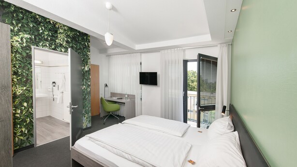 A modern hotel room with a bed, a desk, a chair, and a TV. - Hotel INNdependence (Mainz)