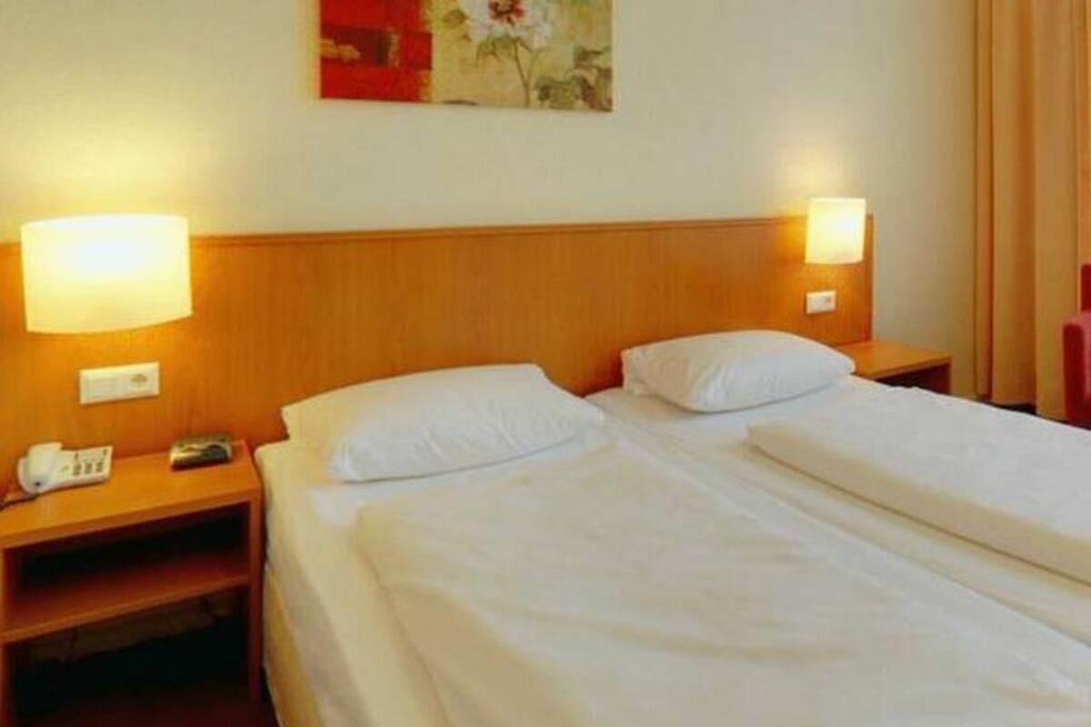 Ein Hotelzimmer mit zwei Betten, Nachttischen, Lampen und einem Bild an der Wand.