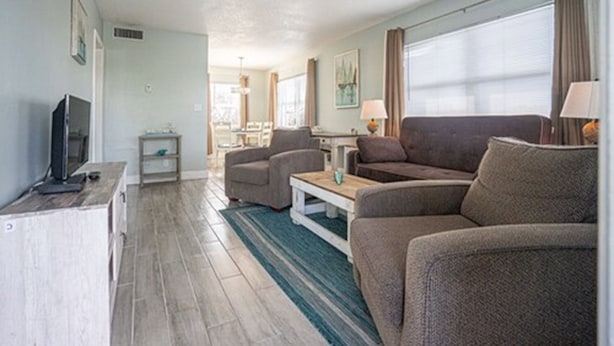 Una sala moderna con un sofá, sillones, una mesa de centro y un televisor sobre un mueble.