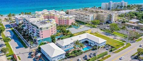 An aerial view of a coastal hotel with multiple buildings, a swimming pool, and a parking lot.