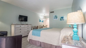 Una habitación de hotel con una cama, un tocador, un televisor y una lámpara.