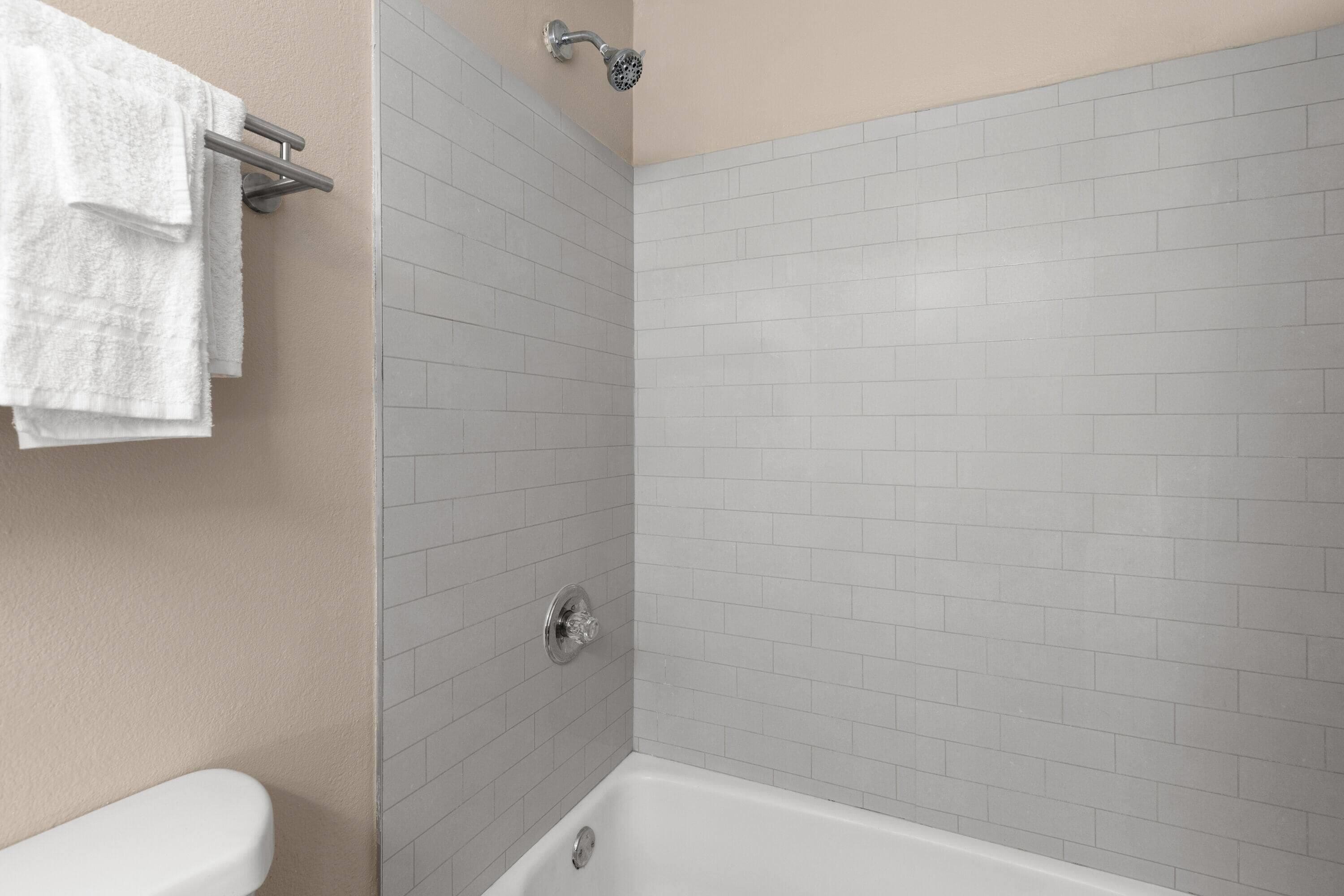 A bathroom with a white bathtub, a toilet, and a towel rack with towels.