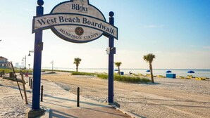 A beach boardwalk sign with 'West Beach Boardwalk' and 'Harrison County' written on it.