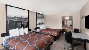 A hotel room with two beds, a desk, a chair, a TV, and a large cityscape painting on the wall.