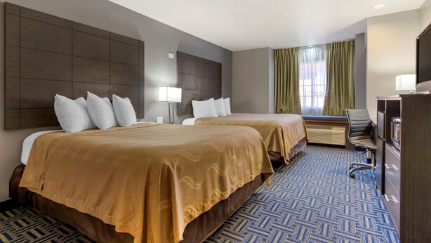 A hotel room with two beds, a desk, a chair, a TV, and a window with curtains. - Quality Inn Sallisaw (Sallisaw)