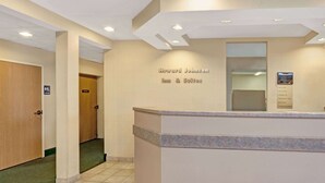 Un área de recepción con un mostrador, un cartel de Howard Johnson Inn & Suites y un directorio en la pared.