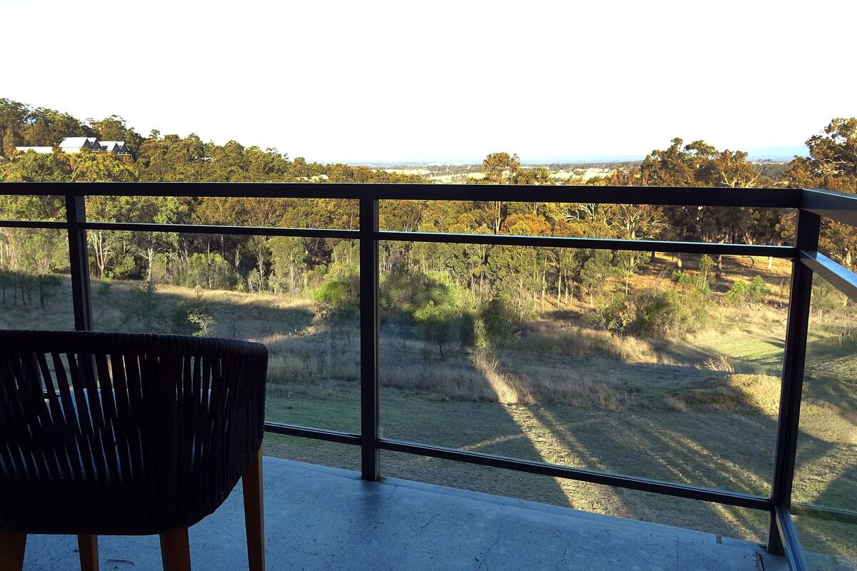 Un balcon offrant une vue sur un paysage rural, avec des arbres et des champs à perte de vue.