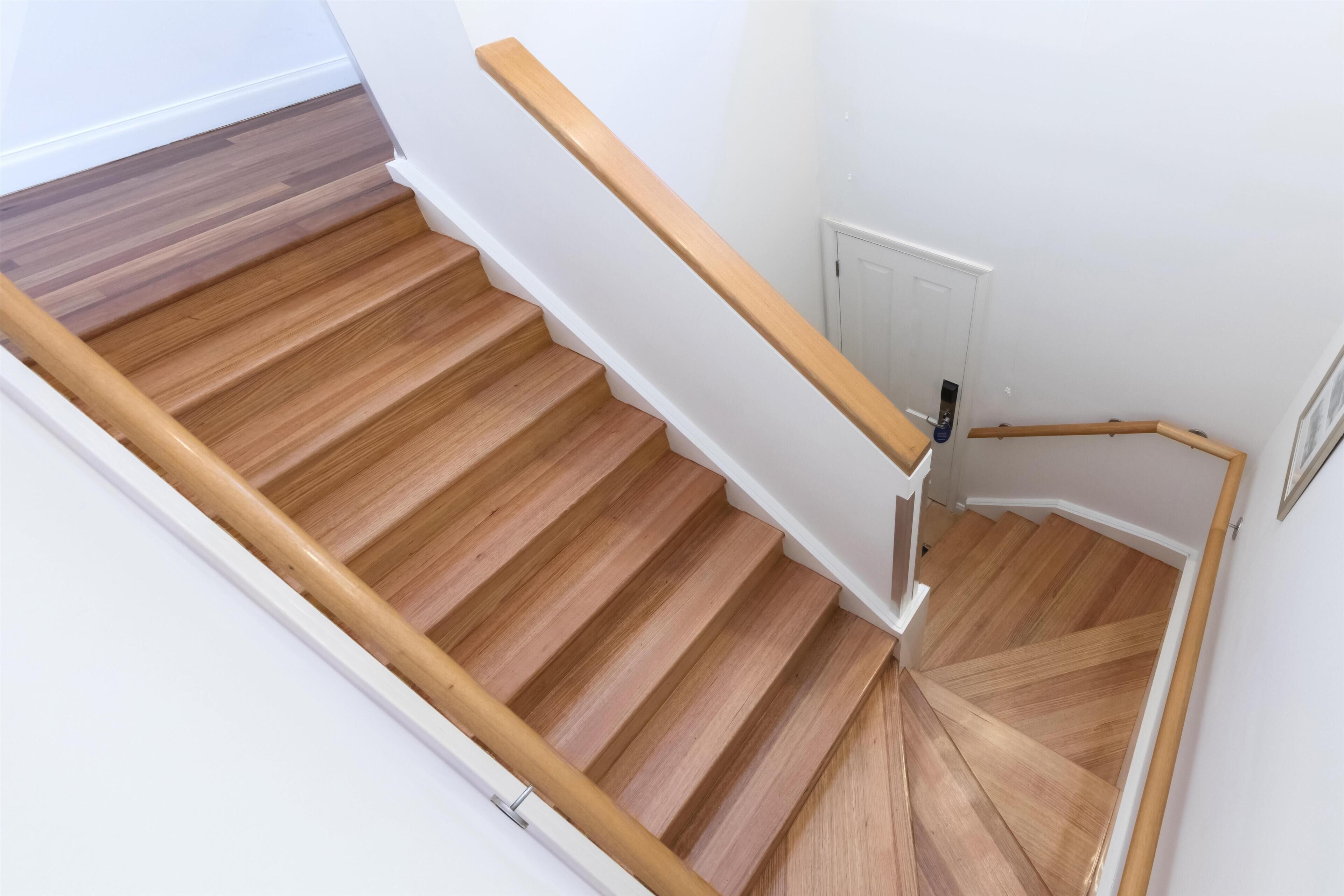A wooden staircase with white walls and a white door at the top.