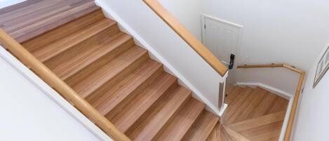 A wooden staircase with white walls and a white door at the top.