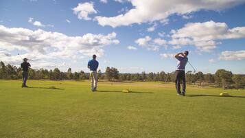 Ein Golfplatz mit drei Spielern in blauen Hemden und schwarzen Hosen.