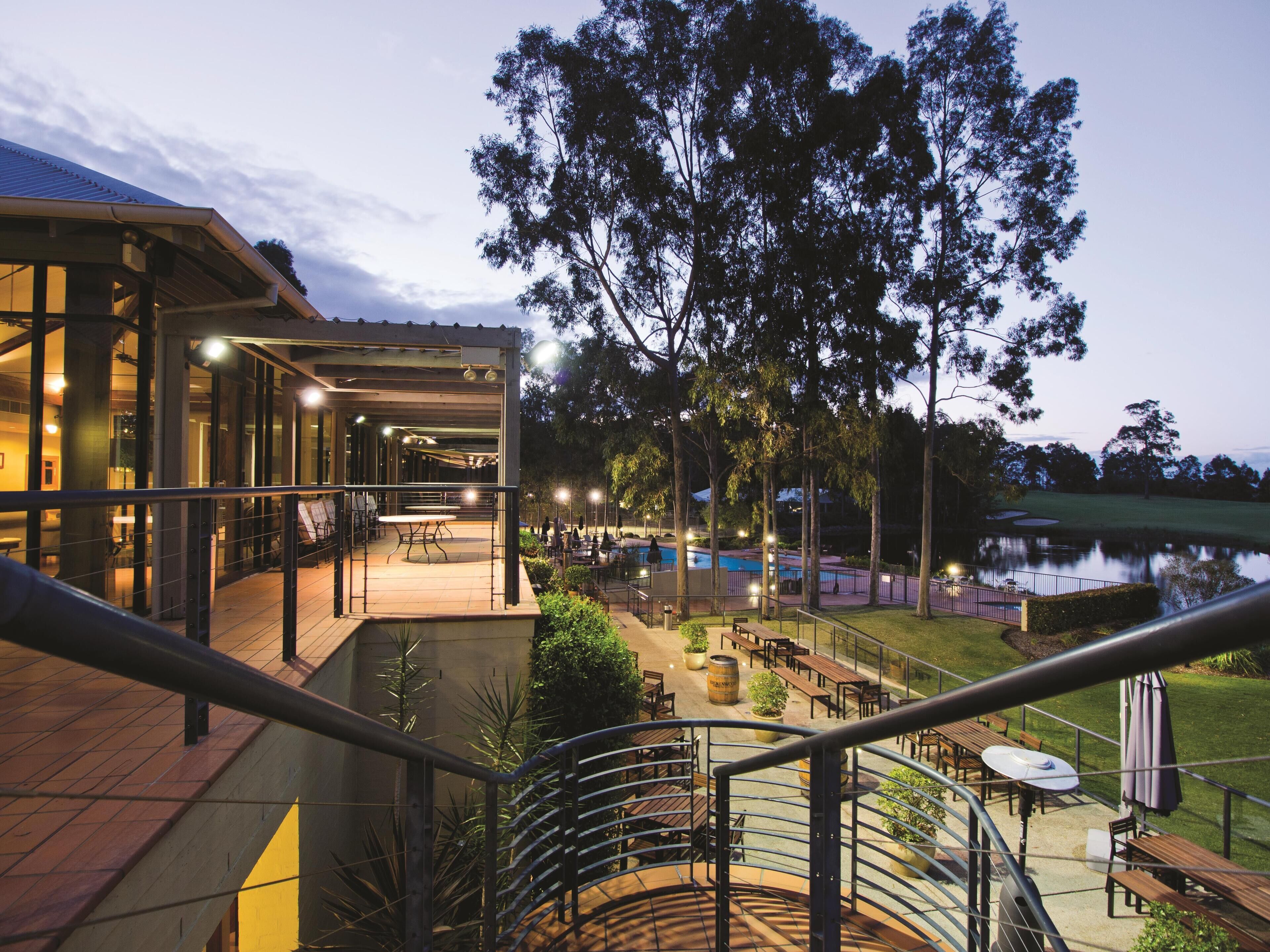 A modern outdoor dining area with a pool and a view of the surrounding landscape.