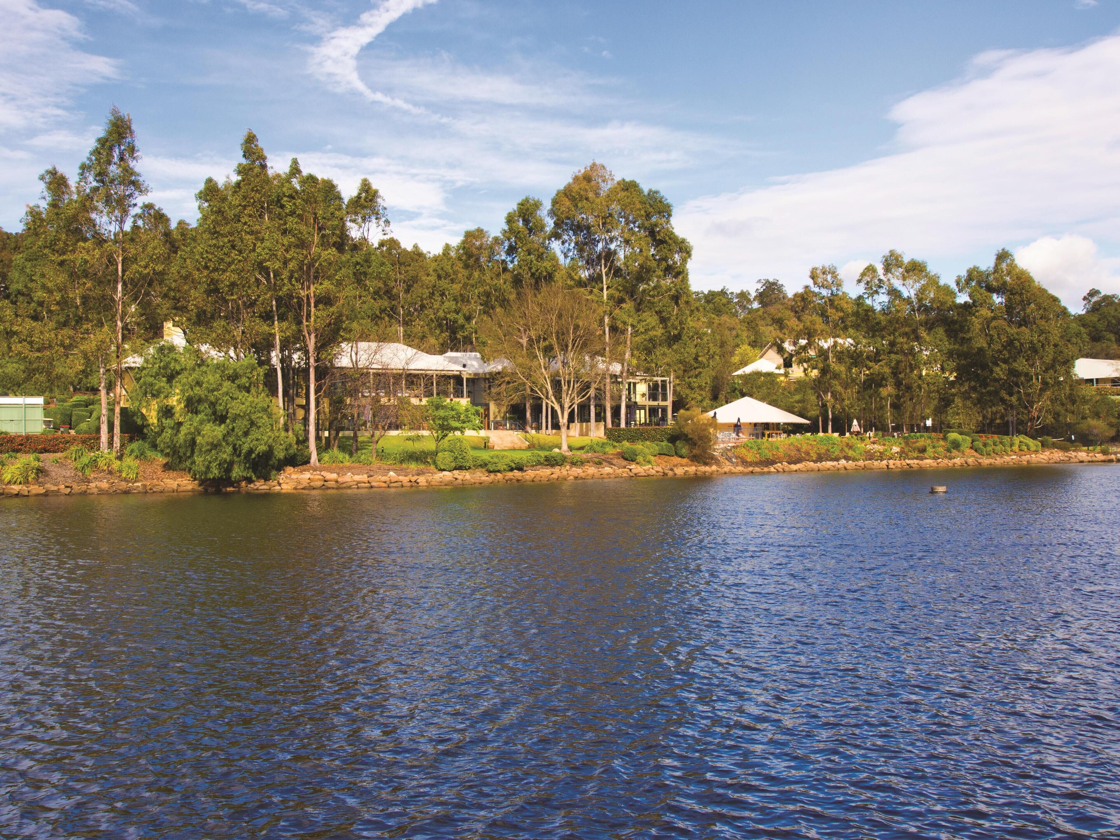 A lakeside property with a house surrounded by dense trees and a calm lake.