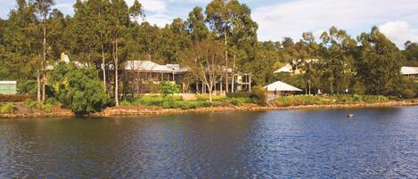 A lakeside property with a house surrounded by dense trees and a calm lake.