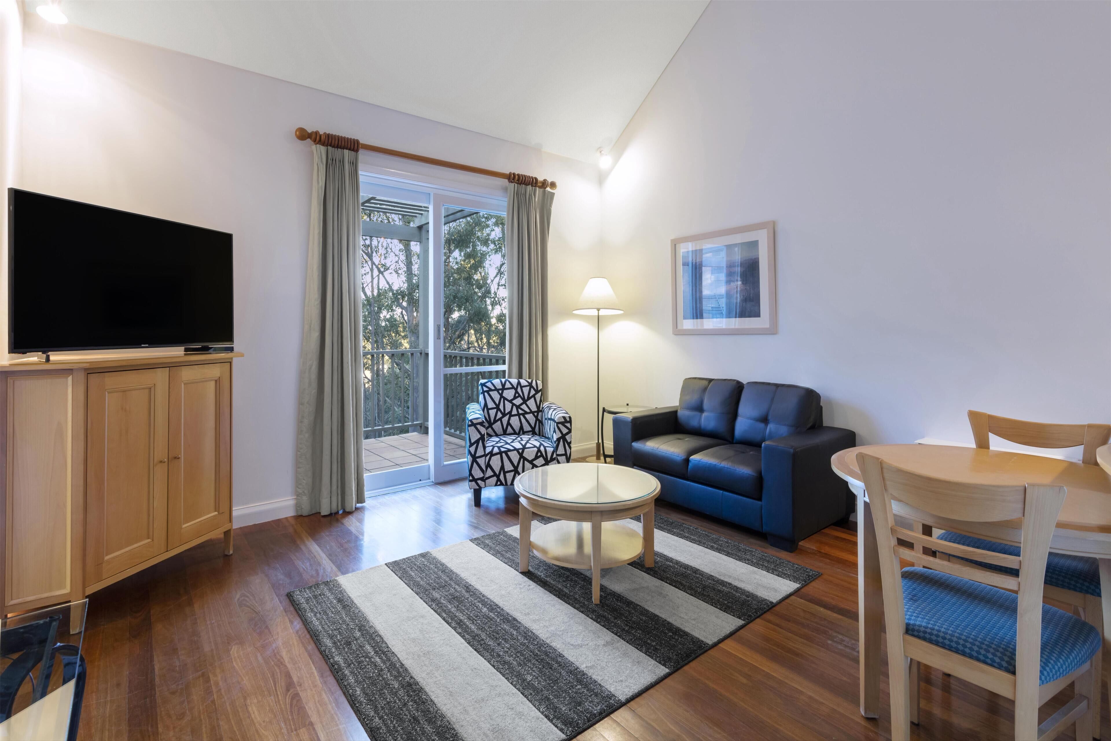 A living room with a flat-screen TV, a sofa, a coffee table, and a dining table with chairs.