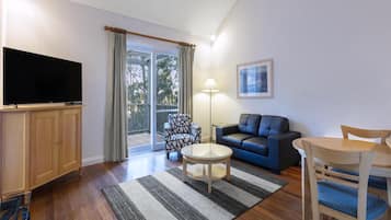 A living room with a flat-screen TV, a sofa, a coffee table, and a dining table with chairs.