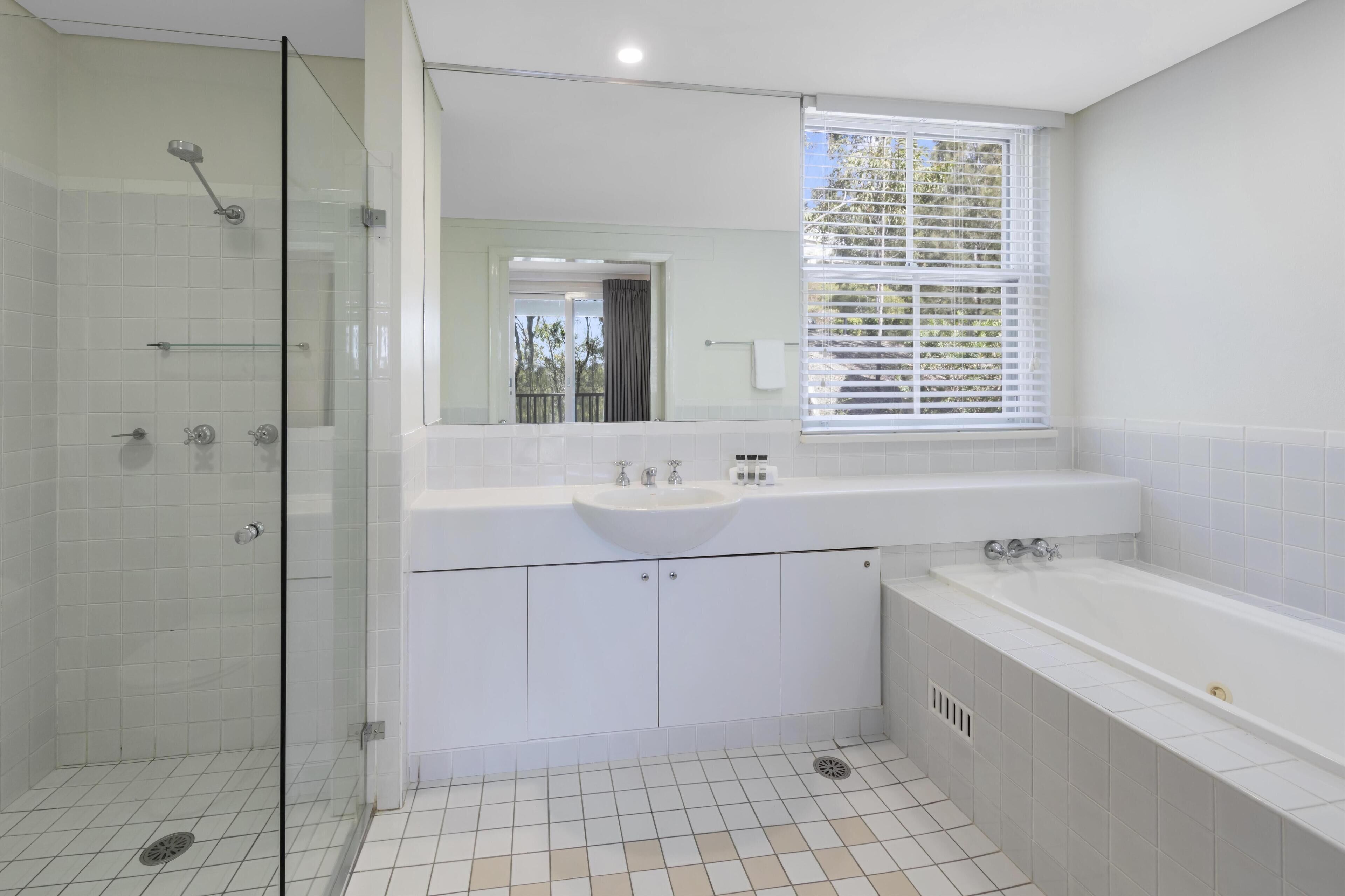 A modern bathroom with a glass-enclosed shower, a large sink, and a bathtub.